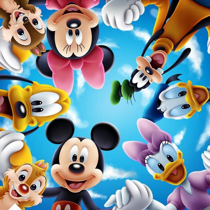 A photo of Disney's Mickey Mouse and friends including Miney Mouse, Goofy, Donald Duck, Daisy Duck, Pluto, Chip, and Dale. The characters are all smiling and are holding hands in a circle looking down at you. Behind them, you can see the blue sky with a number of white fluffy clouds. 